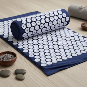 Peut inclure: Un tapis d'acupression bleu foncé et un traversin cylindrique assorti, tous deux recouverts de nombreux disques circulaires en plastique blanc dotés de petites pointes acérées. L'ensemble présente un motif uniforme et répétitif.