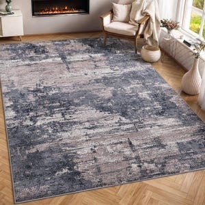 May include: A rectangular area rug featuring an abstract, distressed pattern in shades of charcoal gray, slate blue, and muted beige. The design displays a weathered, textured appearance with horizontal color variations across the surface.
