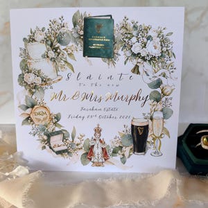 May include: A square wedding invitation card featuring a floral wreath with a green marriage registration form, a two-tier cake, a wax seal, rings, a statue, a pint of stout, and a champagne flute. Text reads Slainte to the new Mr & Mrs Murphy.