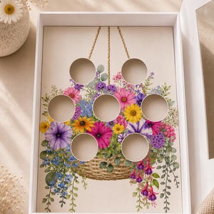 May include: A white box with a floral design featuring a woven basket overflowing with colorful flowers. The box has circular cutouts for displaying items. The flowers include pink, purple, yellow, and blue blooms.