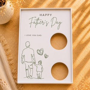 May include: A rectangular white display board featuring the text HAPPY Father's Day and I LOVE YOU DAD. The board includes a green line art illustration of an adult and a child holding hands with two hearts, alongside two circular cutouts on the right.