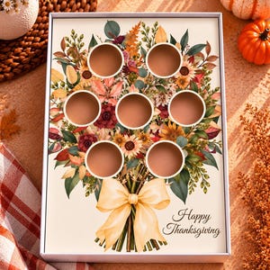Puede incluir: Una caja rectangular blanca con una ilustración impresa de un ramo de flores otoñales con siete recortes circulares. El ramo incluye girasoles, hojas de otoño y bayas, atado con una cinta amarilla y el texto Happy Thanksgiving.