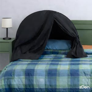 May include: A black bed tent is set up over a bed with a blue pillow and a blue and green plaid comforter. A small black lamp sits on a green nightstand to the left of the bed. The brand name "zDen" is visible.