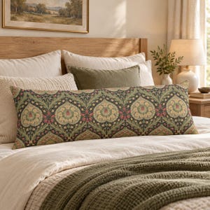 Pode incluir: Uma almofada lombar retangular longa com um fundo verde-escuro e um padrão floral repetitivo em tons de creme, vermelho suave e verde-sálvia. O tecido apresenta um design botânico intrincado com folhas e flores estilizadas.