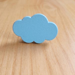 May include: A light blue cloud-shaped object with a smooth, matte finish. The item features a rounded, scalloped edge design that mimics the appearance of a stylized cloud. The surface is uniform in color and texture, presenting a simple, flat form.
