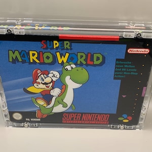 Pode incluir: Uma caixa de videogame Super Mario World para o sistema Super Nintendo Entertainment, encerrada em uma capa protetora de acrílico transparente. A caixa mostra Mario montado em Yoshi em um fundo azul com o texto Erforsche neun Welten.