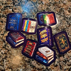 May include: A collection of rectangular stickers featuring illustrations of fantasy book covers. Titles include A Vow in Vengeance, City of Gods and Monsters, Stalked by Seduction and Shadow, Mayhem and the Mortal, The Wolf and the Crown of Blood, and Bloody Black.