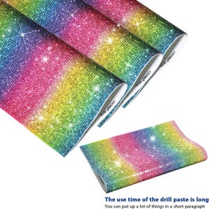 May include: A set of rainbow-colored rhinestone sheets featuring a dense, sparkling gradient of blue, green, yellow, and pink crystals. The sheets have a flexible backing and are labeled with the text CROWN #513L on the white edge.
