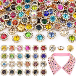 May include: A collection of circular, multi-colored rhinestone buttons, each featuring a central faceted gem surrounded by a ring of small clear crystals in a gold-tone setting. A pink fabric collar is decorated with these buttons.