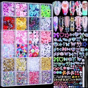 May include: A clear plastic storage organizer containing twenty-four compartments filled with assorted nail art decorations, including colorful bows, flowers, pearls, stars, and rhinestones, alongside a set of decorated fingernail samples.