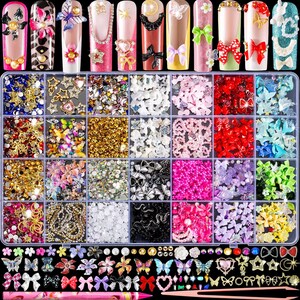 May include: A multi-compartment storage box filled with assorted nail art charms including miniature bows, butterflies, stars, hearts, flowers, and rhinestones in various colors, accompanied by a pair of tweezers and nail tip samples.
