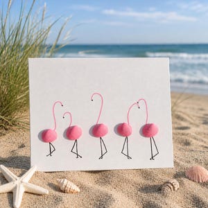 May include: A rectangular white card featuring five pink flamingo figures. Each flamingo is constructed using a small pink seashell for the body, with a hand-drawn pink neck and head, and thin black ink lines for the legs and feet.