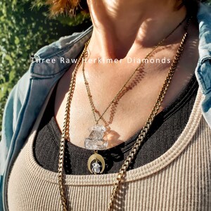 Pu&ograve; includere: Un set di collane a strati composto da una catena color oro e una catena sottile con tre diamanti Herkimer grezzi. Il ciondolo include un ciondolo a mezzaluna color oro che sostiene un piccolo cristallo trasparente e due cristalli sovrapposti.