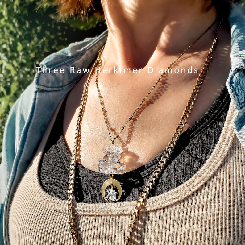 Pu&ograve; includere: Un set di collane a strati composto da una catena color oro e una catena sottile con tre diamanti Herkimer grezzi. Il ciondolo include un ciondolo a mezzaluna color oro che sostiene un piccolo cristallo trasparente e due cristalli sovrapposti.
