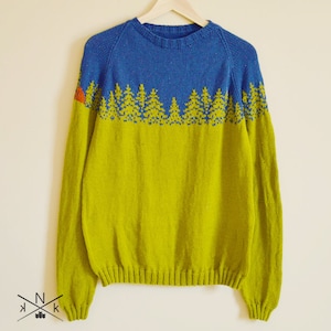 May include: A green and blue knitted sweater with a pattern of trees and a small orange tent. The sweater has a crew neck and long sleeves.
