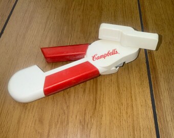 Abrelatas manual vintage de sopa Campbell's, rojo y blanco, herramienta publicitaria de cocina.