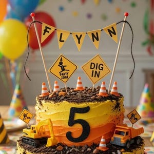 Op de afbeelding: Een verjaardagstaart met twee lagen, versierd met gele, oranje en bruine glazuur, met speelgoed bouwvoertuigen en verkeerskegels. De taart is bekroond met een banner met de tekst "Flynn" en borden met "Party Zone" en "Dig In". Kleurrijke ballonnen en feestborden omringen de taart.
