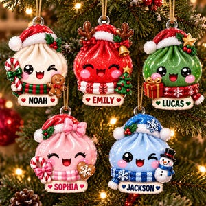 Könnte beinhalten: Fünf personalisierte Weihnachtsanhänger in Form von lächelnden Teigtaschen mit festlichen Mützen und Schals. Jeder Anhänger trägt ein Namensschild: Noah mit Lebkuchenmann, Emily mit Glocke, Lucas mit Geschenk, Sophia mit Keks und Jackson mit Schneemann.