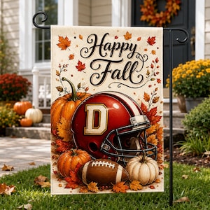 May include: A rectangular garden flag featuring the text Happy Fall in black script. The design includes a red football helmet with a white letter D, a brown football, and orange pumpkins surrounded by scattered autumn maple leaves in shades of red, orange, and yellow on a light beige background.