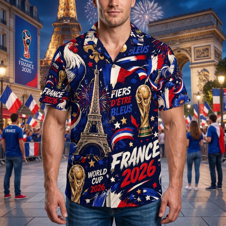 May include: A short-sleeved button-down shirt with a navy blue background, featuring a design of the Eiffel Tower, a rooster, and the words "France 2026." The shirt also includes the words "Fiers d'&ecirc;tre Bleus" and images of the World Cup trophy.