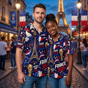 May include: A couple wearing matching blue, white, and red button-down shirts with Eiffel Tower and rooster designs. The shirts have "France 2026" and "Fiers d'&ecirc;tre Bleus" text. The background shows the Eiffel Tower and French flags.