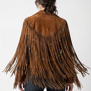 Könnte beinhalten: Braune Wildlederjacke mit langen Fransen und bunten Perlenakzenten. Die Jacke hat einen klassischen Kragen und eine taillierte Passform. Ein stilvolles Kleidungsstück für einen Bohème- oder Western-Look.