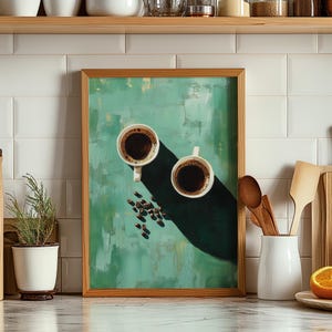 Könnte beinhalten: Ein gerahmter Kunstdruck mit einem texturierten mintgrünen Hintergrund, zwei weißen Tassen mit schwarzem Kaffee und verstreuten dunklen Kaffeebohnen. Die Komposition zeigt lange, scharfe Schatten, die über die Oberfläche geworfen werden.