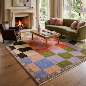 May include: A large rectangular area rug featuring a multi-colored patchwork design of squares in shades of blue, green, orange, brown, and pink. The rug has a decorative border with small floral motifs and a fringe along the short edges.