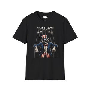 Puede incluir: Camiseta negra con un diseño gráfico del Tío Sam como marioneta, controlada por hilos. El diseño utiliza una combinación de colores rojo, blanco y azul, con la marioneta usando un sombrero de copa y un traje.