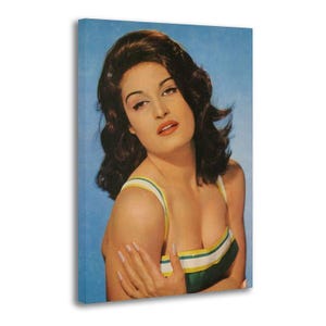 May include: Vintage-style canvas print featuring a woman with dark hair and makeup. She wears a green, yellow, and white striped top against a blue background. The image has a retro aesthetic, reminiscent of classic pin-up art.