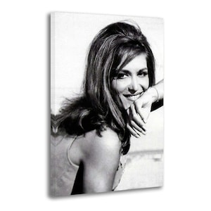 May include: Black and white portrait of a smiling woman with long hair, resting her arm on a surface. The image is a canvas print, showcasing a vintage aesthetic.
