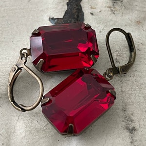 May include: A pair of earrings with large, rectangular, red gemstone drops and antique gold-toned hooks.