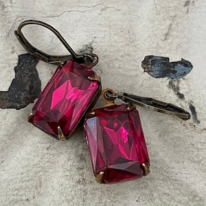 May include: A pair of earrings with a pink, faceted, rectangular stone and a bronze hook.