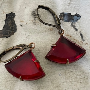 May include: A pair of earrings with red glass teardrop-shaped stones and antique brass hooks.