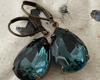 May include: A pair of teardrop-shaped earrings with dark blue faceted glass stones and antique brass-toned leverback closures.