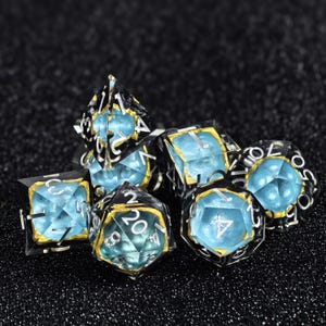 Peut inclure: Un ensemble de dés polyédriques avec une coque extérieure transparente, un cœur texturé bleu vif et des accents dorés. Les dés présentent des chiffres argentés gravés sur les faces, incluant un dé à vingt faces, un dé à douze faces et d'autres.