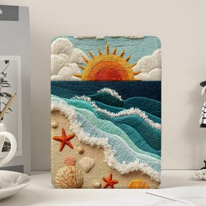 May include: Embroidered beach scene with a vibrant orange sun setting over turquoise waves. The artwork features white foamy waves, seashells, and starfish on a sandy shore. The design is detailed and colorful, evoking a coastal theme.