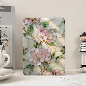 May include: A rectangular case with a stained glass design featuring pink cherry blossoms, green leaves, and gold-coloured stems. The background is a light, off-white colour with a network of lines.