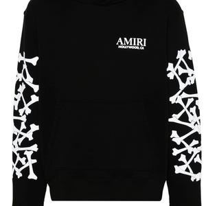May include: Black hoodie with white bone designs on the sleeves. The hoodie has a front pocket and the word "AMIRI" in white, with "HOLLYWOOD, CA" underneath. A casual, streetwear-style garment.