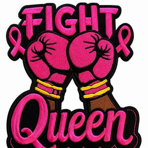 May include: An embroidered patch featuring the text FIGHT in pink letters above two pink boxing gloves with yellow wristbands. Two pink awareness ribbons flank the gloves. The word Queen is embroidered in pink below the gloves on a black background.