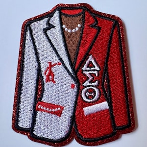 May include: An embroidered patch shaped like a blazer with a split design. The left side is white with a red figure and pocket detail, while the right side is red with the Greek letters Delta Sigma Theta in white. A brown collar and pearl necklace are visible.