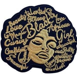 May include: A dark navy blue embroidered patch featuring a gold-colored stylized face surrounded by words including Beauty, Talented, Strong, Black, Magic, Love, African, Girl, Curvy, Confident, Educated, Pretty, Greatness, Brave, Successful, and Excellent.