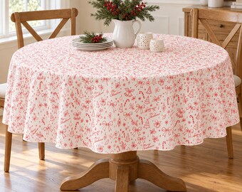 Könnte beinhalten: Eine runde Tischdecke mit weißem Hintergrund und einem wiederkehrenden roten Linienmuster aus Weihnachtsbäumen, Schleifen, Zuckerstangen und dem Schriftzug Merry Christmas, drapiert über einem runden Holztisch.