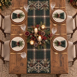 May include: A wooden dining table set for four with a dark green plaid table runner featuring gold fleur-de-lis embroidery. Each place setting includes a woven charger, white plate, dark green napkin with pine and berries, and gold cutlery.