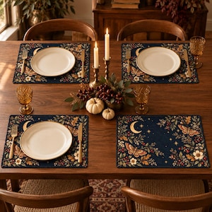Peut inclure: Quatre sets de table rectangulaires sur fond bleu marine ornés d'un motif botanique de papillons de nuit, de croissants de lune, d'étoiles, de feuilles de chêne et de baies. Chaque set comprend une assiette blanche, une fourchette et un couteau.