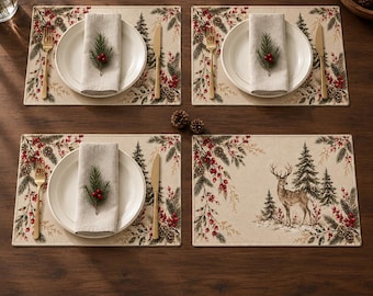 Könnte beinhalten: Vier rechteckige Platzsets mit einem weihnachtlichen Druck aus Tannenzweigen, Tannenzapfen und roten Beeren. Drei Platzsets sind mit einem weißen Teller, einer beigen Leinenserviette mit Tannenzweig, einer goldenen Gabel und einem Messer gedeckt.