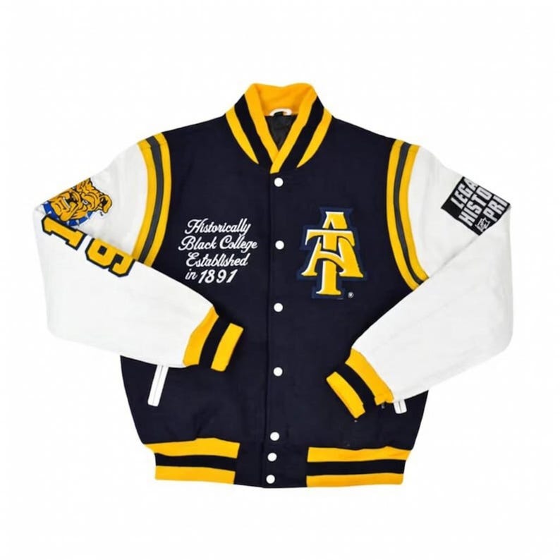 Pu&ograve; includere: Giacca college blu navy e bianca con dettagli gialli. La giacca presenta la scritta "Historically Black College Established in 1891" e un logo "AT" giallo. Le maniche sono bianche, il colletto e i polsini gialli.