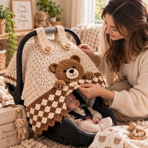 Könnte beinhalten: Ein cremefarbener und brauner gehäkelter Autositzbezug mit einem zentralen Teddybären-Applikation, zwei geknöpften Riemen und einem karierten Randmuster. Der Bezug liegt über einem schwarzen Babysitz mit einem schlafenden Baby in beiger Kleidung.
