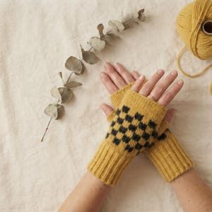 May include: A pair of mustard yellow fingerless gloves featuring a black checkered pattern on the back of the hand. The gloves are constructed with a ribbed cuff and a knit texture, showcasing a consistent color scheme throughout the design.