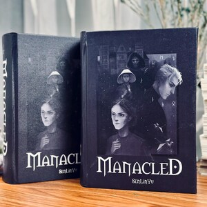May include: Two hardcover books with the title "Manacled" in white lettering. The covers feature a dark, gothic illustration with figures and architectural elements. The author's name, SenLinYu, is also visible.